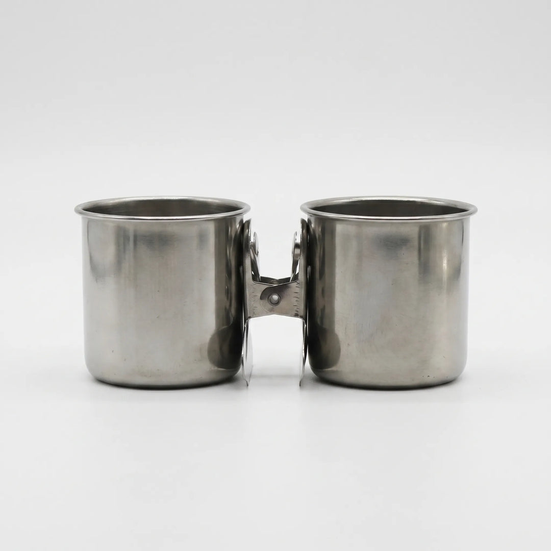 Two steel cups with the clips pressed together between them, shown from the front on a plain background. 7