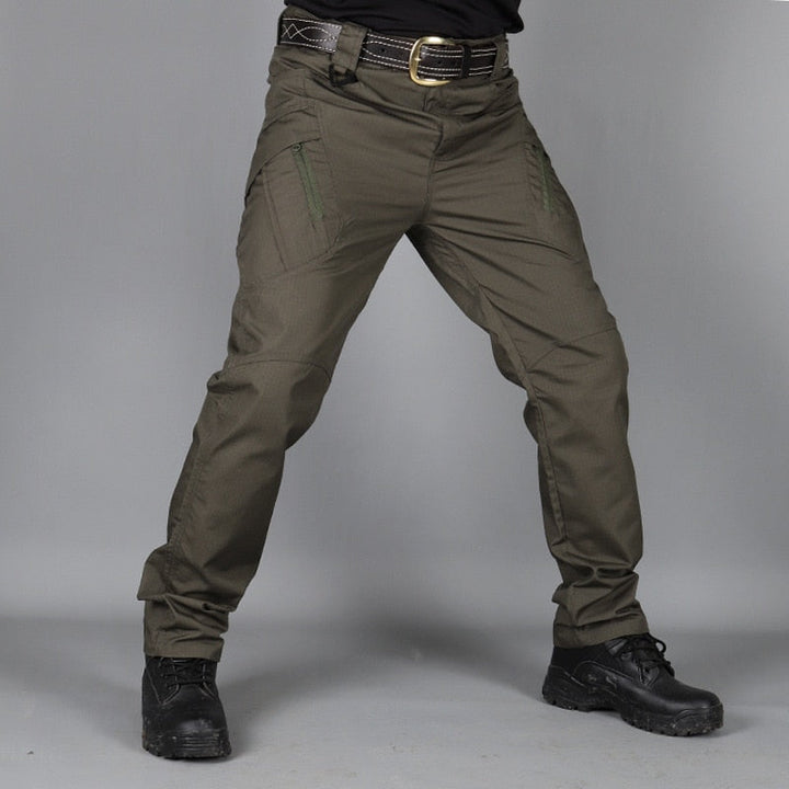 Men's olive green cargo pants front view with a belt and black boots, showing zippered thigh pockets.