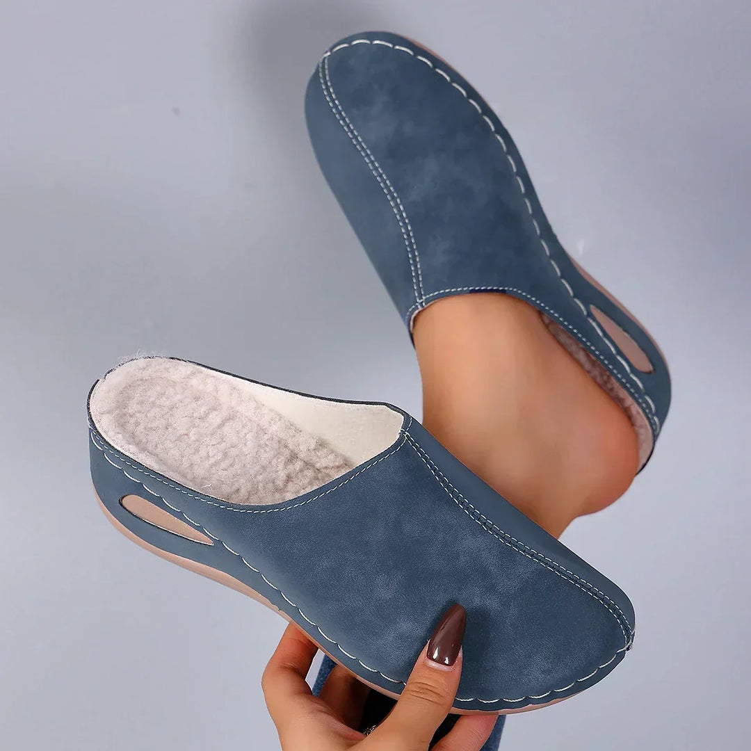 Blue suede-look backless clogs with white contrast stitching and the plush fleece lining and cutout in the wedge sole.