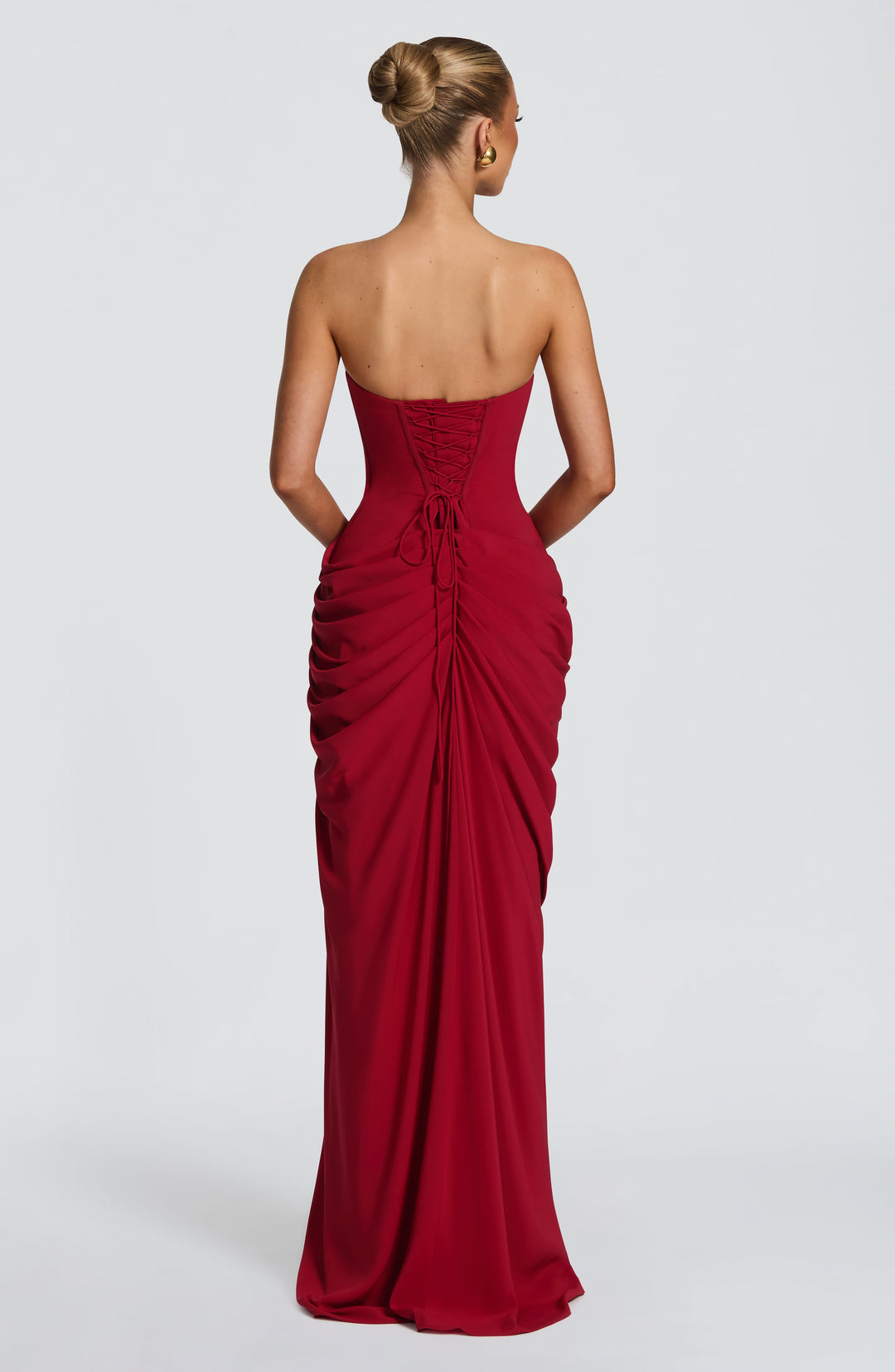 Back view of the red strapless dress showing corset lacing with loose ties and gathered, draped skirt. 28