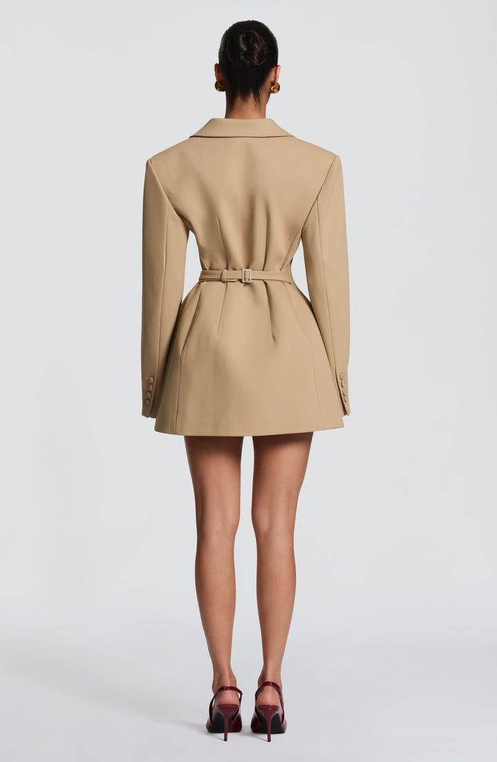 Back view of the camel blazer dress showing a buckled belt at the waist, darted seams, a flared hem and buttoned cuffs. 23