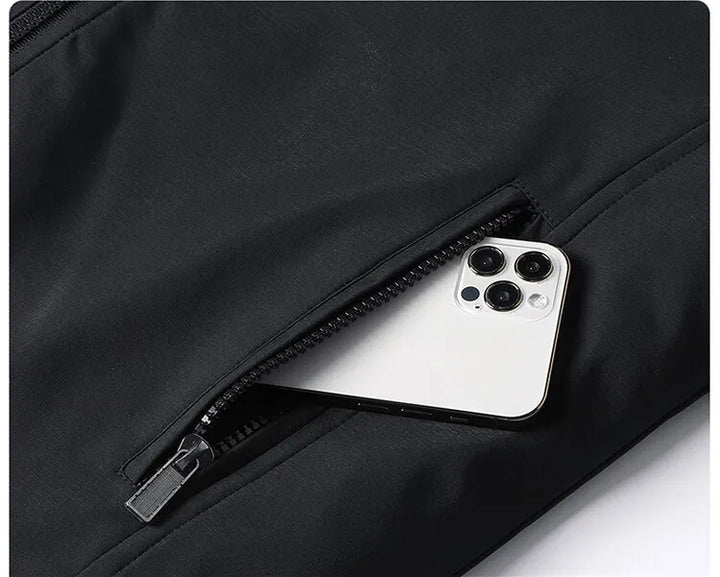 Close-up of the zippered side pocket on the black jacket, with a white smartphone partly tucked inside. 7