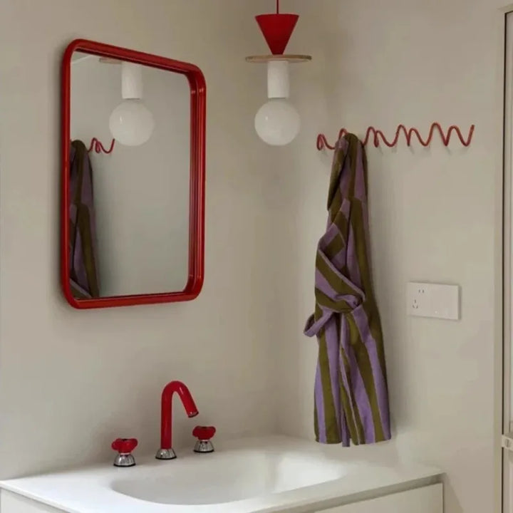 Silver metal wall rack detail with three hooks.