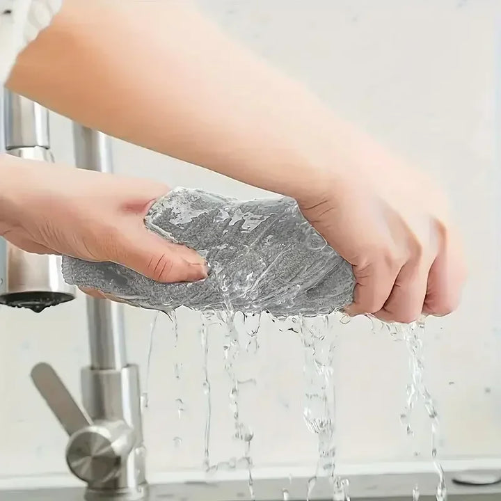Grey microfiber cleaning cloth being wrung out over a kitchen sink, another view.