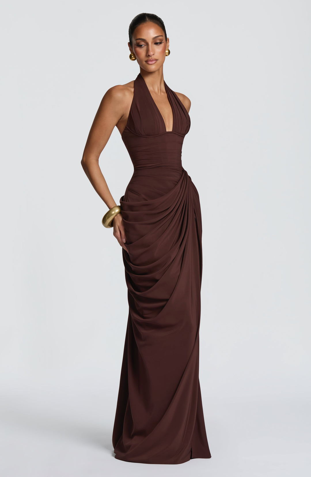 Angled view of the brown dress with the model glancing down, highlighting the pleated corset waist and gathered side drape. 28