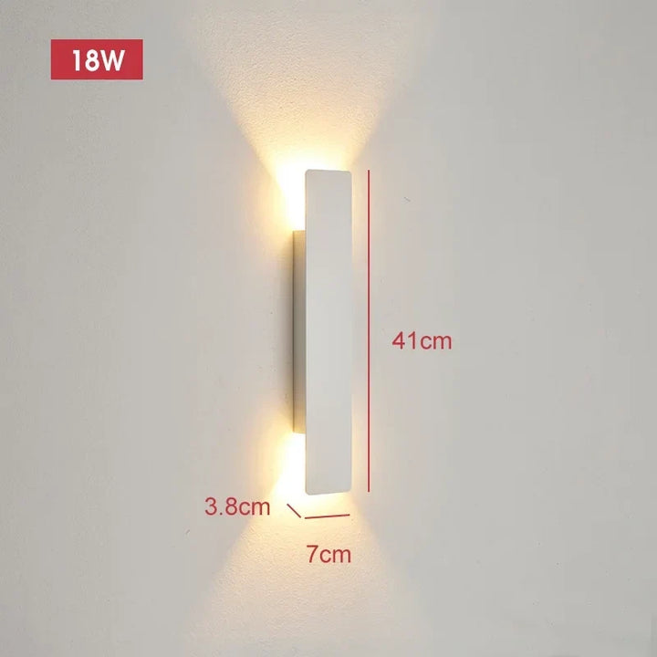White wall light mounted on a wall, glowing up and down, with dimension lines marking its size.