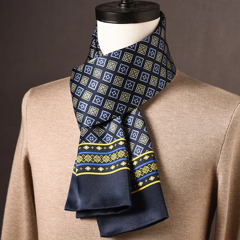 Dark navy silk scarf with blue and yellow square motifs and a yellow-and-blue striped border, draped on a mannequin in a tan sweater. 22