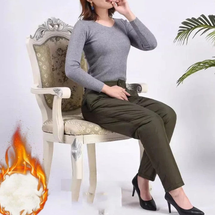 Frau in grauem Pullover und grüner Hose auf antikem Stuhl, Baumwolle, Flammensymbol.