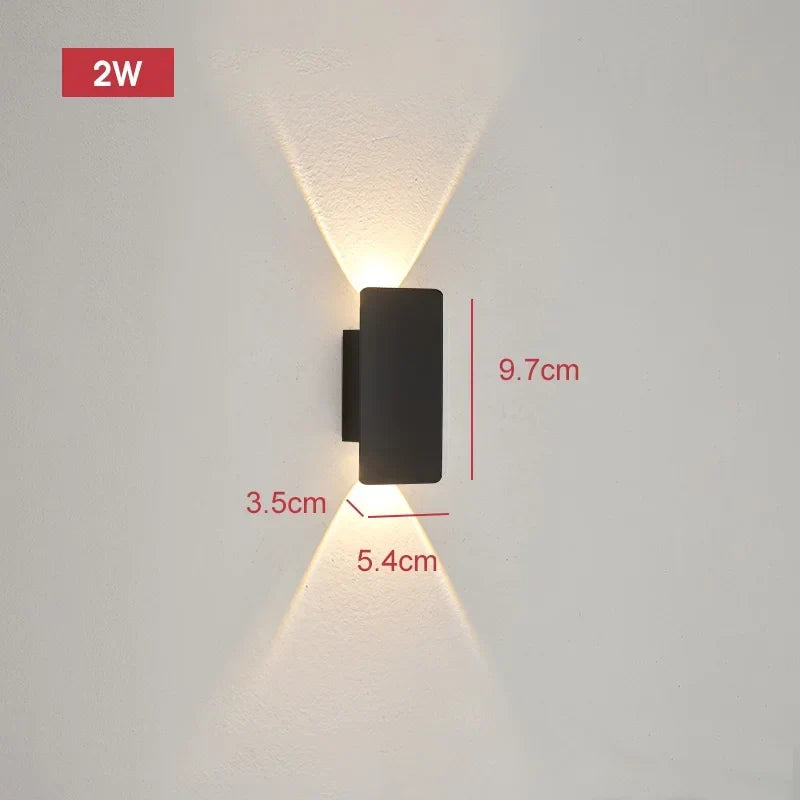 Smallest black wall light on a pale wall projecting narrow beams up and down, with dimension lines marking its size.