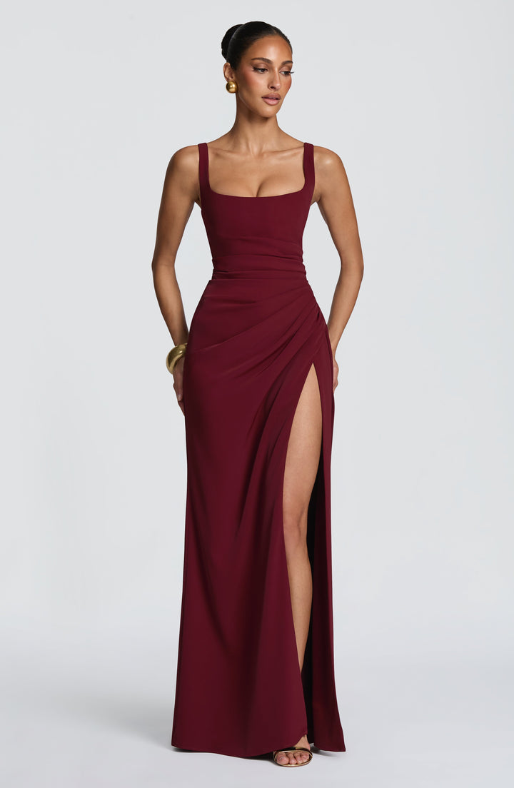 Burgundy Camille Maxi Dress on a model, front view with gold earrings and bracelet and the high slit.