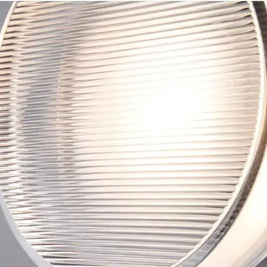 Close-up of horizontal ribbed glass on the lamp front, with soft light glowing through the center.