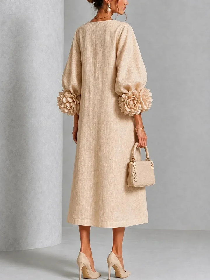 Back view of the beige midi dress on a model, showing the plain back, puffed sleeves and large rose cuffs. 7