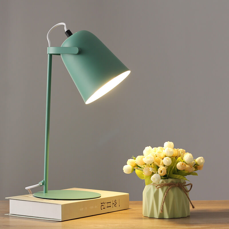 Green version of the lamp lit on a book next to a vase of cream roses 9