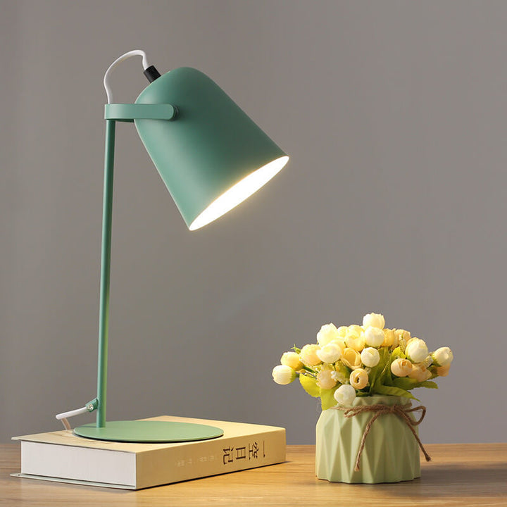 Green version of the lamp lit on a book next to a vase of cream roses 9