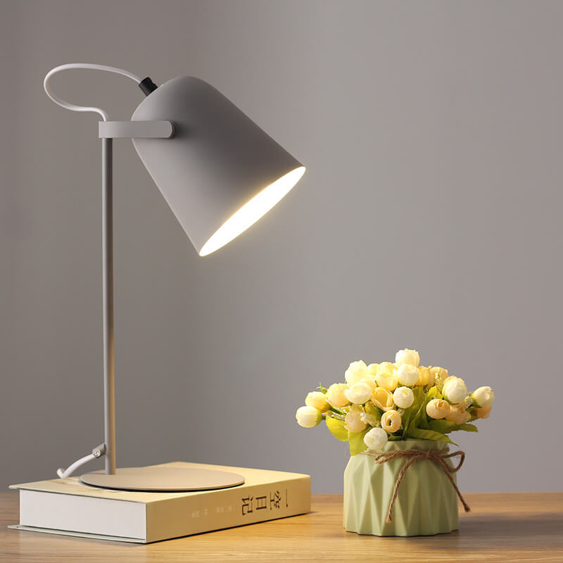 Light gray version of the lamp glowing on a book beside a small vase of flowers 10