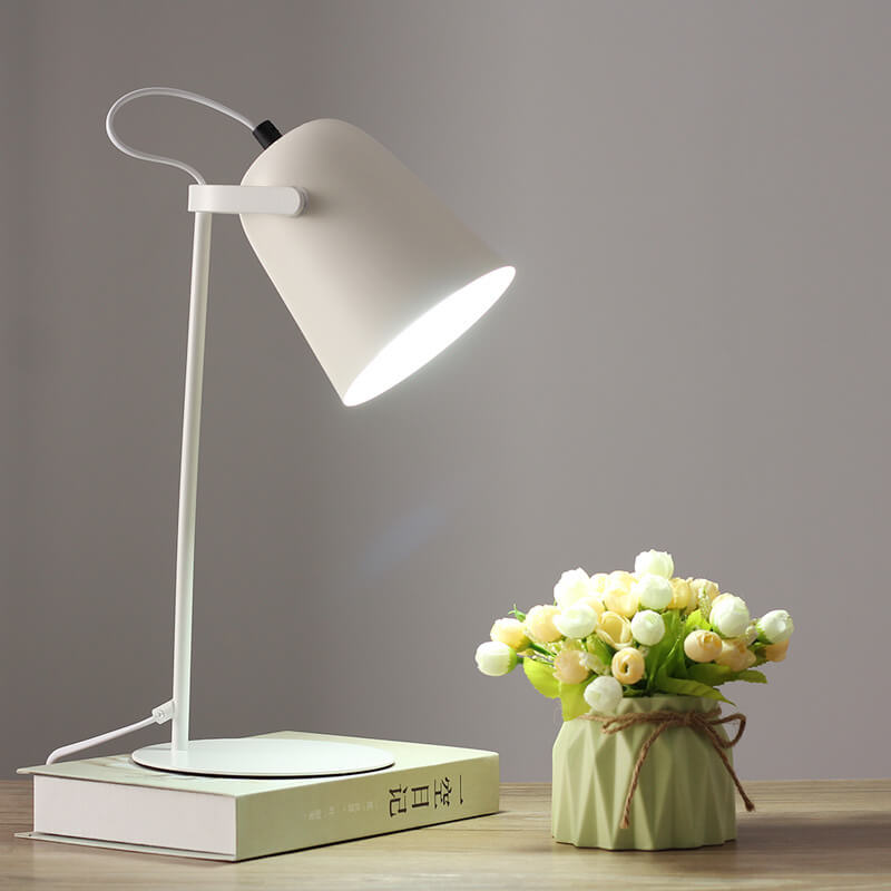White version of the lamp switched on, set on a book next to a flower vase 11
