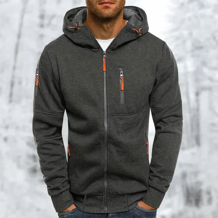 Man wearing the dark gray zip-up hoodie with orange zipper pulls, a textured knit look and ribbed hem.