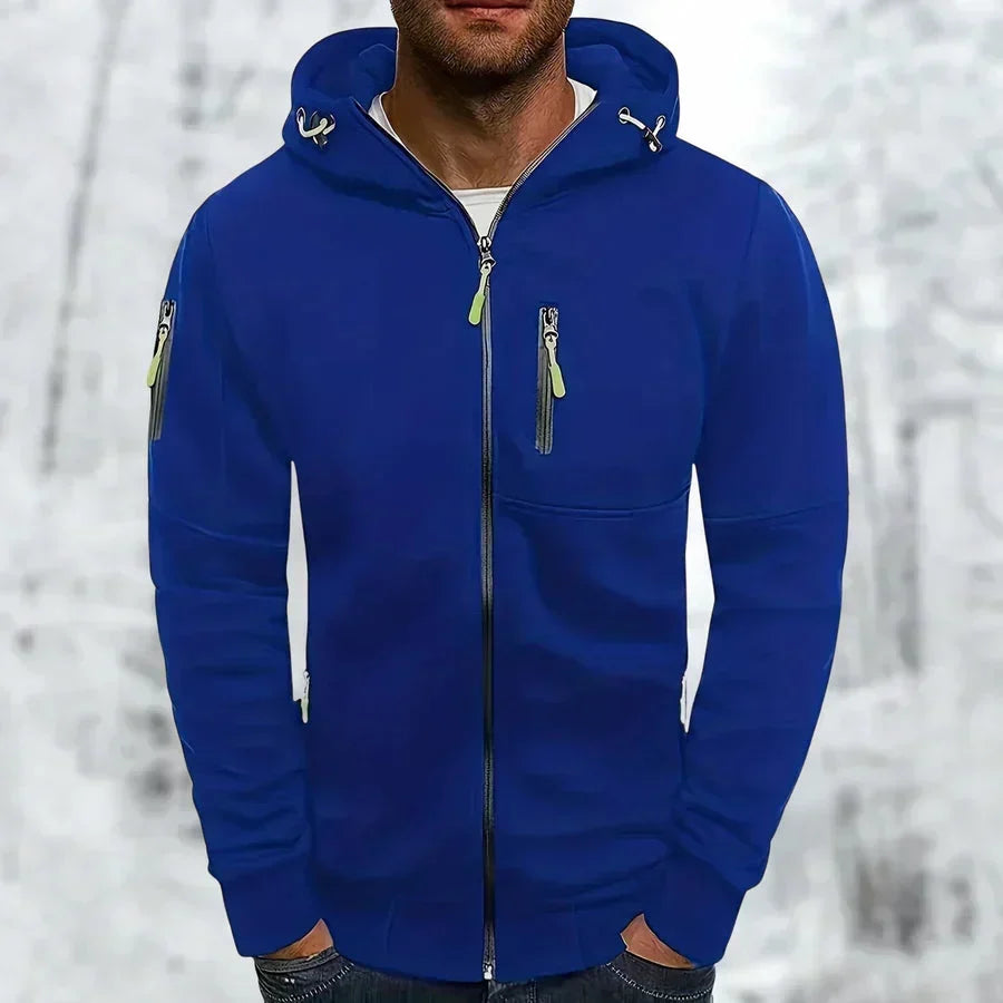 Man wearing the royal blue zip-up hoodie with lime green zipper pulls, hands in pockets.