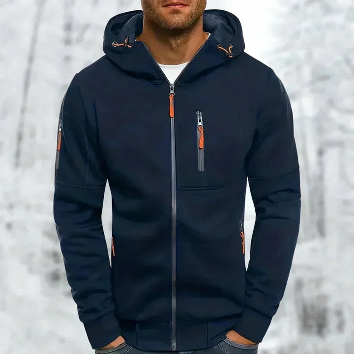 Man wearing the navy blue zip-up hoodie with orange zipper pulls and ribbed cuffs.