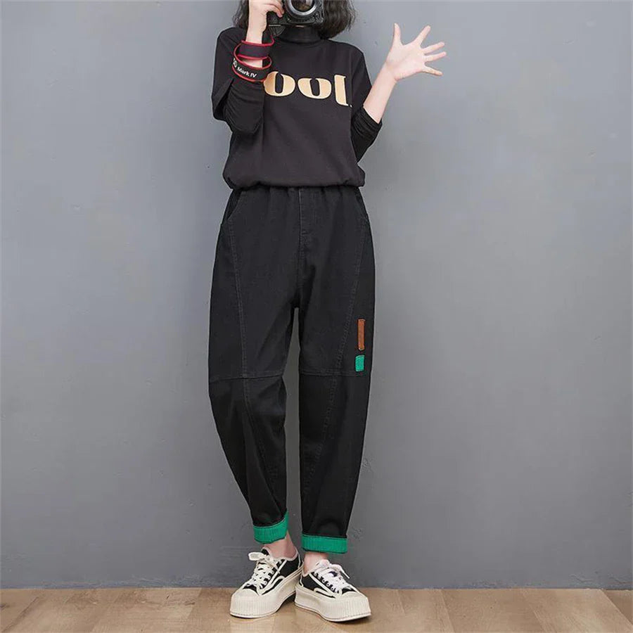 Frau in schwarzem "Cool"-Shirt und schwarzer Hose mit grünen Details, lässiger Stil.