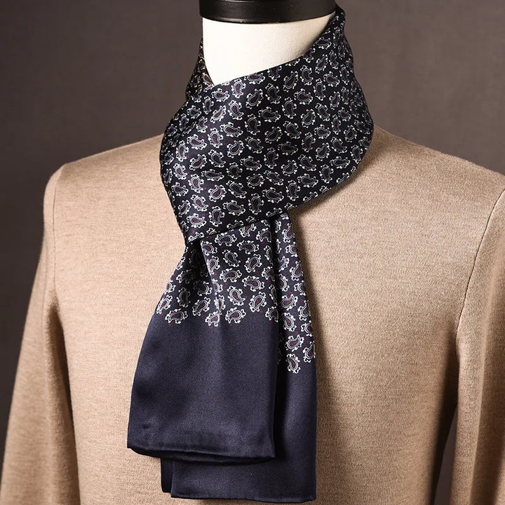 Navy silk scarf with small white paisley print above a plain navy end, draped on a mannequin over a tan sweater. 26