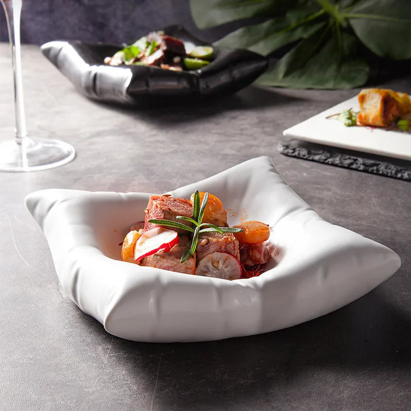 White cloud-shaped porcelain bowl holding a plated meat dish with radish slices and rosemary.