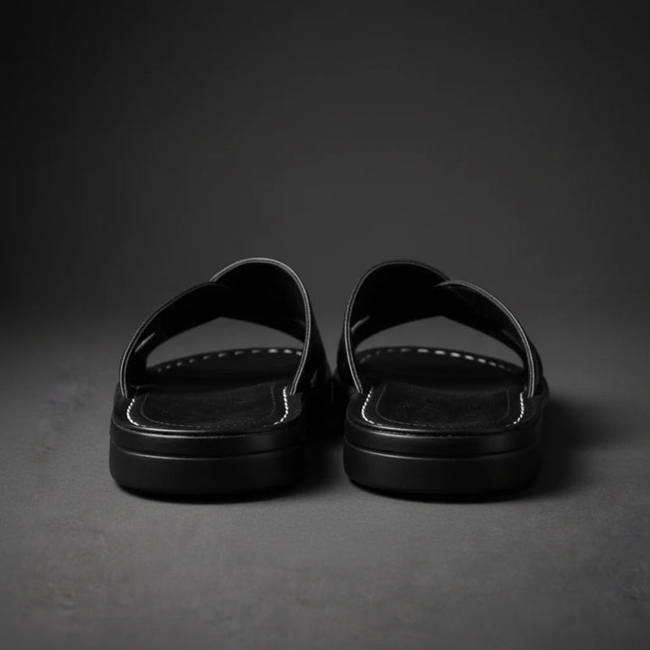 Rear view of black crossed-strap sandals showing the thick layered black sole and white stitching along the footbed. 9