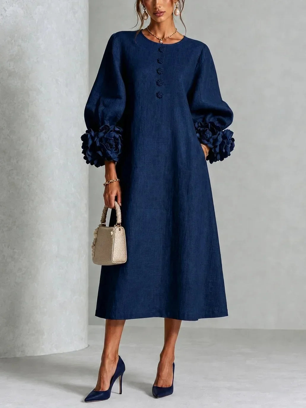 Model wears the navy blue version of the midi dress with large rose cuffs, floral buttons down the front and matching pumps. 2
