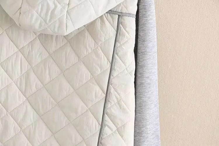 Beigefarbene, gesteppte Jacke mit Kapuze und grauen Ärmeln, modische Winterbekleidung.
