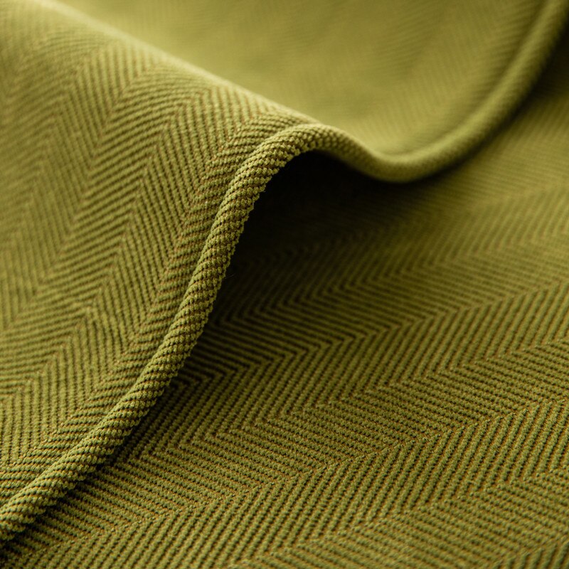 Close-up of green chenille fabric showing its woven texture and folded edge.