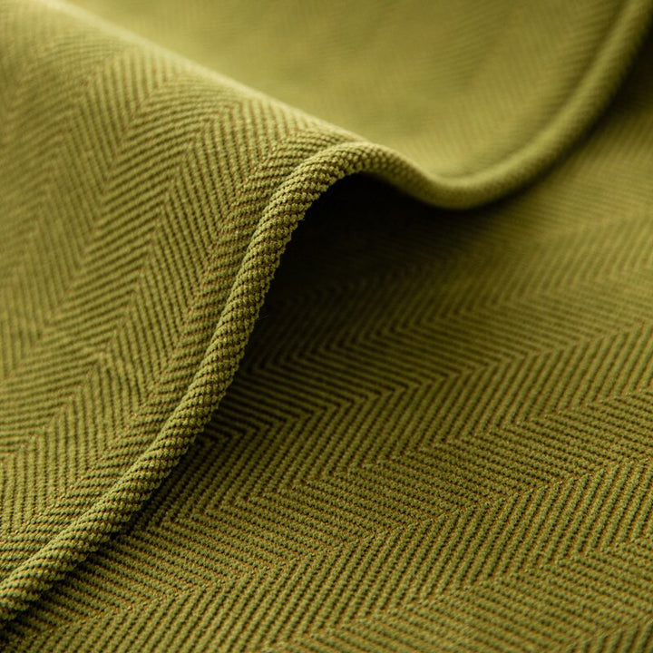 Close-up of green chenille fabric showing its woven texture and folded edge.