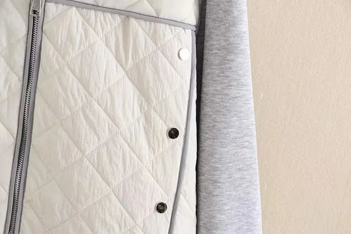 Weiße gesteppte Jacke mit silbernem Reißverschluss und grauem Futter, modisch und warm.