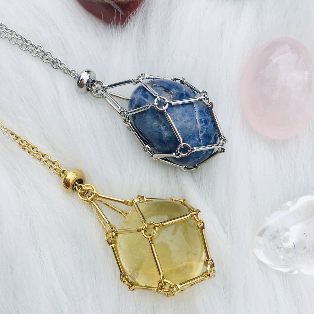 Another view of silver and gold cage necklaces holding blue and yellow stones on white fur. 3