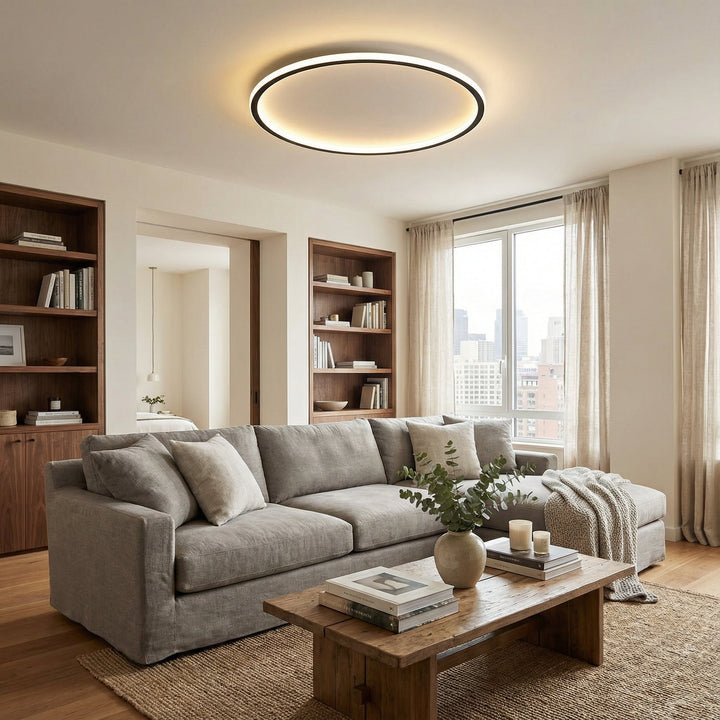 Ring ceiling light glowing above a living room with a gray sectional sofa, wooden coffee table and built-in bookshelves. 4