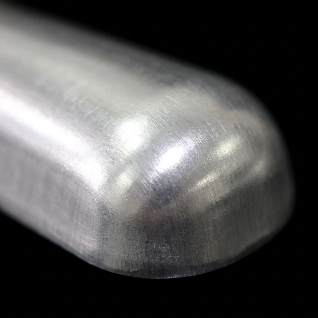 Extreme close-up of the scoop's rounded, brushed metal end, showing fine scratches and reflections against a black background. 3