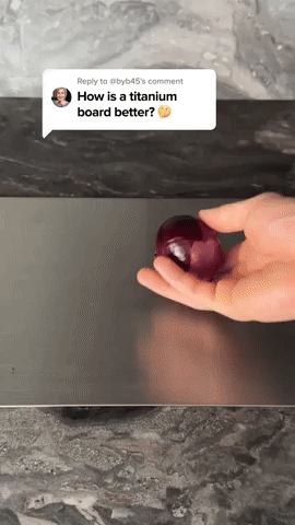 Hand holds a red onion above a flat dark metal board on a marble countertop, with a viewer's question overlaid. 5