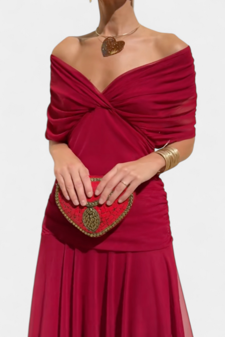 Close-up of the red dress's twisted off-the-shoulder neckline and ruched waist, with a heart pendant necklace and red clutch. 11