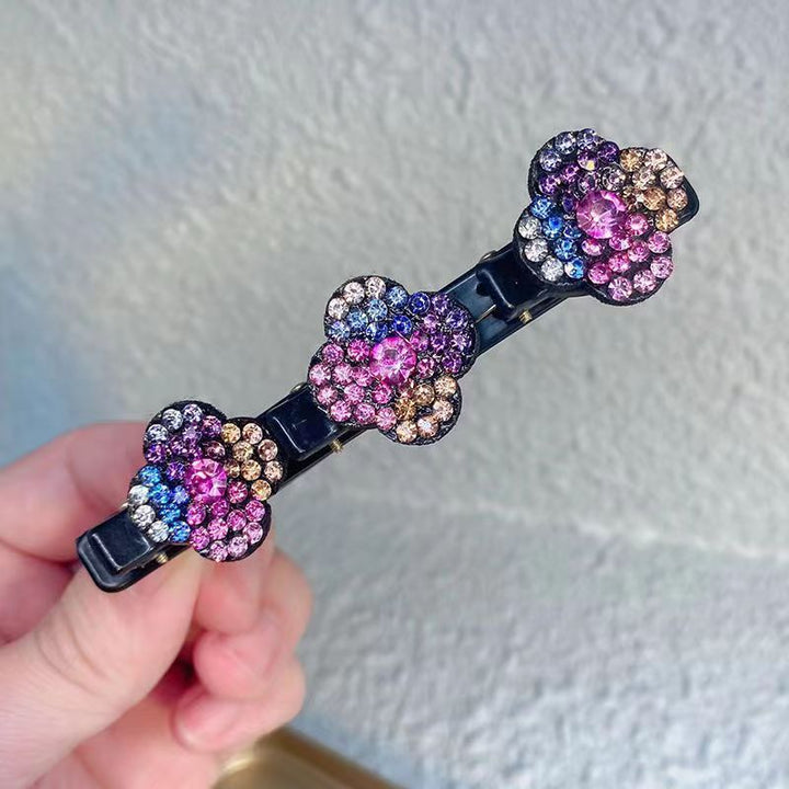 Hand holding a black clip with three multicolor rhinestone flowers in pink, blue and amber 5