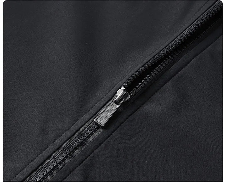 Extreme close-up of the black jacket's front zipper with its metal pull and chunky coil teeth on smooth fabric. 6