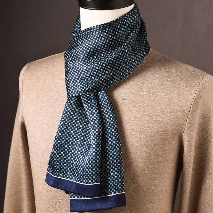 Navy silk scarf with a small teal and cream checkered print and a thin white-lined edge, draped on a mannequin over a tan sweater. 24