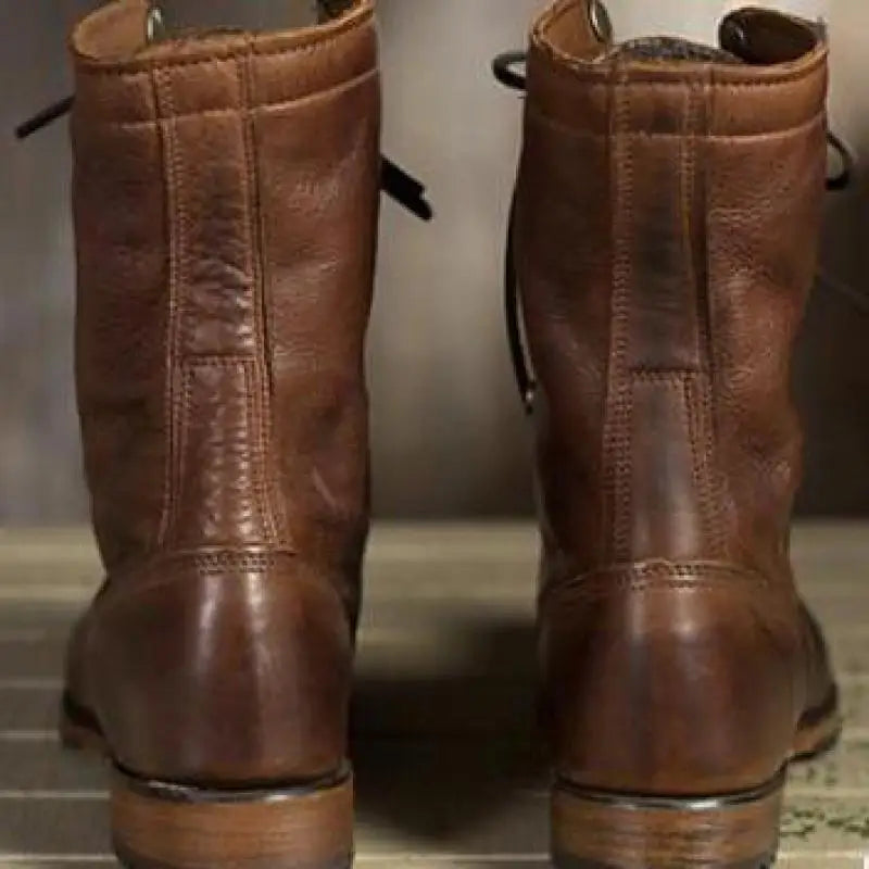 Back view of a pair of brown leather boots showing the vertical center seam, stitched heel panel and low stacked heels. 2