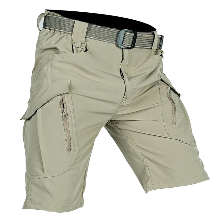 Light khaki cargo shorts with flap pockets, zippered pocket openings, and a webbing belt with a dark buckle.