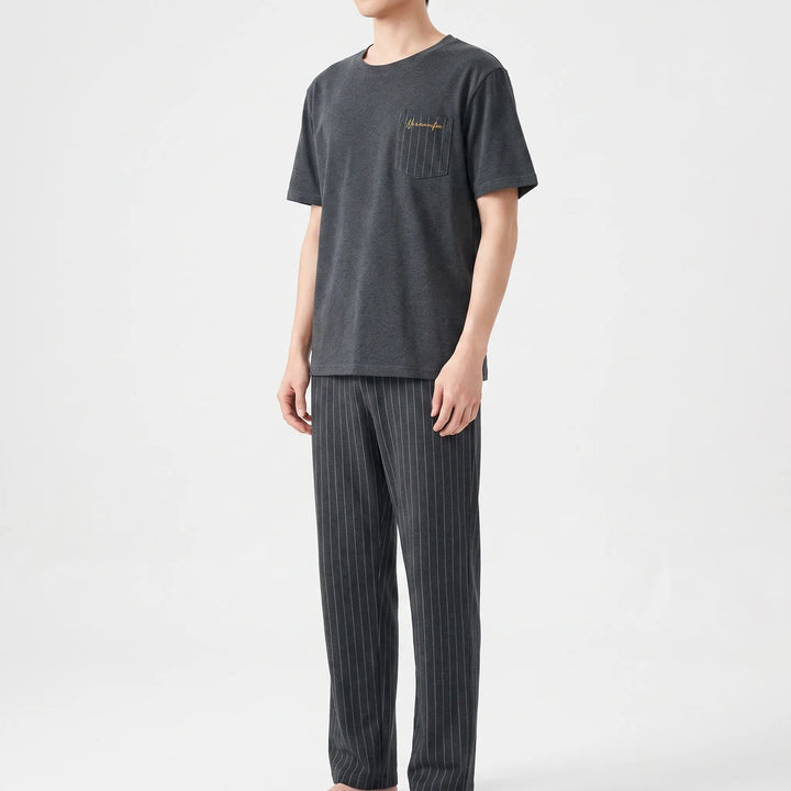 Three-quarter view of a model in the charcoal gray tee with striped pocket and straight-leg pinstriped pants. 4