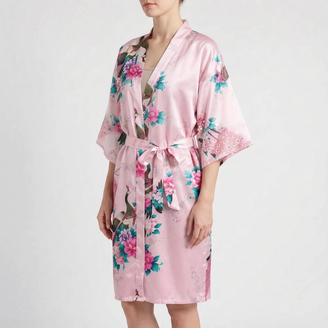 Woman wearing the robe in a light pink colorway with peacock and peony print and a tied belt. 6