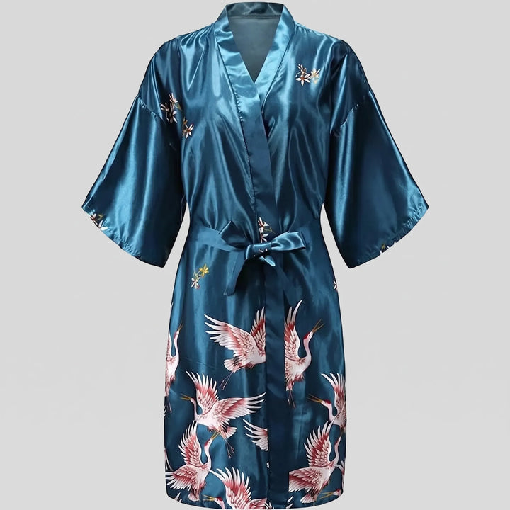 Teal satin version of the short kimono robe laid flat, belt tied in a bow, with cranes along the lower skirt. 10