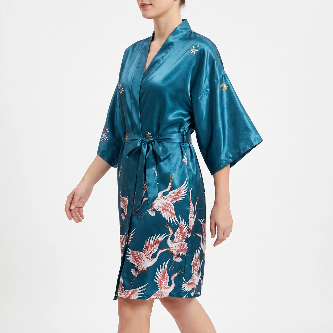 Side view of a model walking in the teal satin robe, belt tied in a bow, with wide kimono sleeves. 4