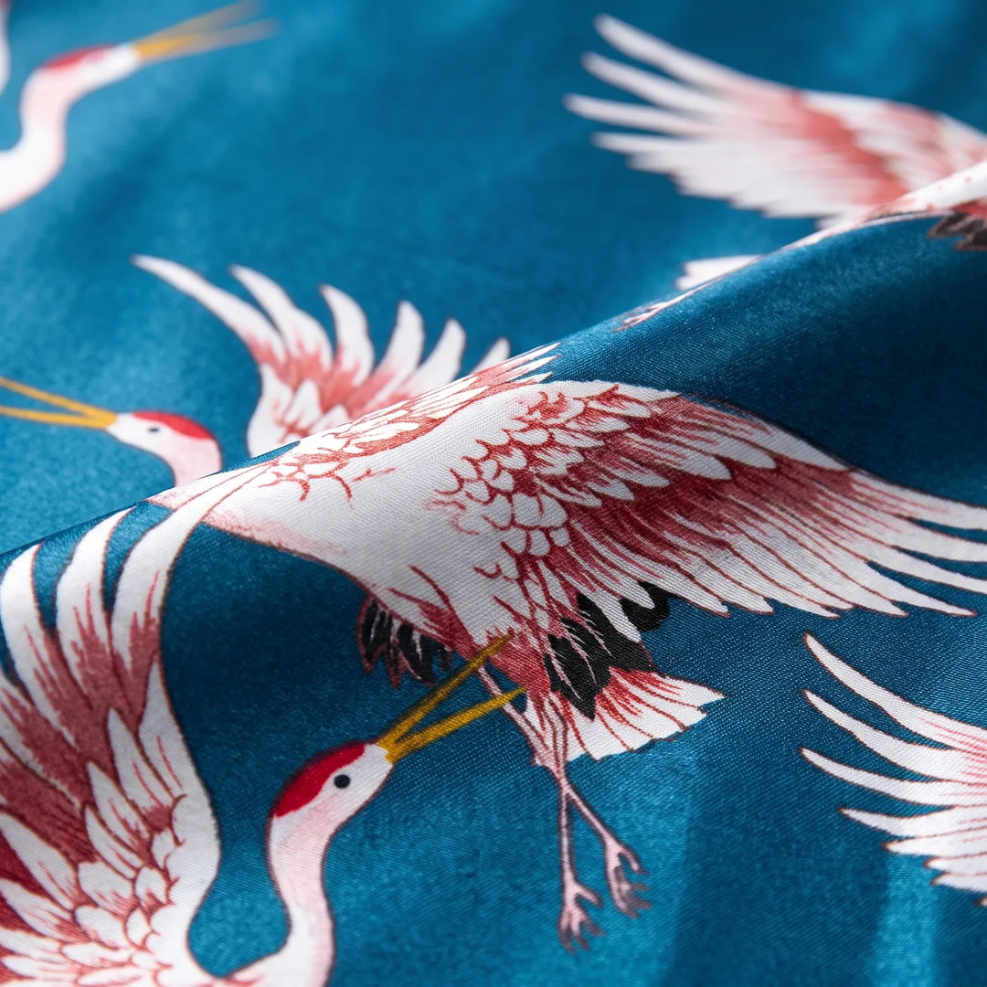 Close-up of the satin fabric folded to show the printed red-crowned cranes with pink-tipped wings on teal. 5