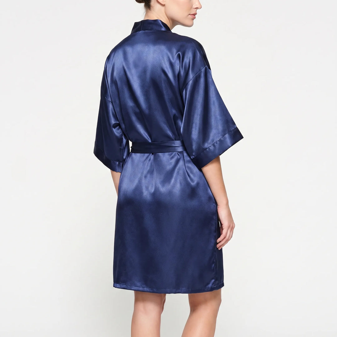 Back view of a model wearing the navy satin kimono robe, showing the wide sleeves, shoulder seams and belt tied at the waist. 3