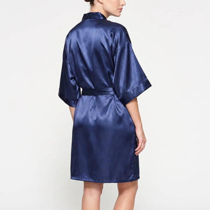 Back view of a model wearing the navy satin kimono robe, showing the wide sleeves, shoulder seams and belt tied at the waist. 3