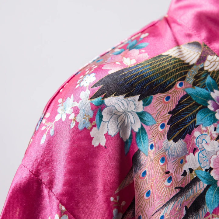 Close-up of the shoulder seam and satin sheen on the hot pink robe, with peacock feathers and cherry blossoms printed on it. 5